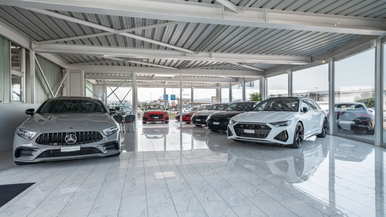 Showroom von Sport Automobile in Schafisheim mit Mercedes-AMG und Audi RS auf hellem Steinboden